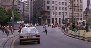 Movie still from “Kiss of the Spider Woman” (1985), directed by Hector Babenco – A busy city street with people walking and cars driving on it; Extreme Wide shot, High angle