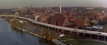 Movie still from “Kiss the Girls” (1997), directed by Gary Fleder – An aerial view of a city with a train on a bridge; Extreme Wide shot, High angle
