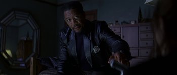 Movie still from “Kiss the Girls” (1997), directed by Gary Fleder – A man in a leather jacket is sitting in a dark room; Close Up shot, Over the shoulder angle