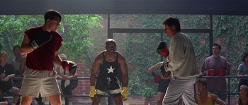Movie still from “Kiss the Girls” (1997), directed by Gary Fleder – A man wearing boxing gloves standing in front of other people; Wide shot, Low angle