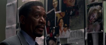 Movie still from “Kiss the Girls” (1997), directed by Gary Fleder – A man in a suit and tie looking at a wall of photos; Close Up shot, Over the shoulder angle