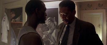 Movie still from “Kiss the Girls” (1997), directed by Gary Fleder – Two men standing next to each other in front of a picture; Close Up shot, Over the shoulder angle