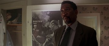 Movie still from “Kiss the Girls” (1997), directed by Gary Fleder – A man standing in front of a poster of dexter; Close Up shot, Low angle
