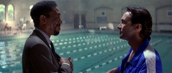 Movie still from “Kiss the Girls” (1997), directed by Gary Fleder – Two men are talking in front of a swimming pool; Medium shot, Over the shoulder angle