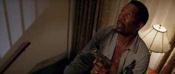 Movie still from “Kiss the Girls” (1997), directed by Gary Fleder – A man holding a gun while sitting in a room; Close Up shot, High angle