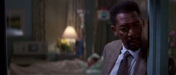 Movie still from “Kiss the Girls” (1997), directed by Gary Fleder – A man wearing a suit and tie sitting in a hospital room; Close Up shot, Over the shoulder angle