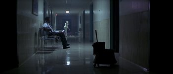 Movie still from “Kiss the Girls” (1997), directed by Gary Fleder – Two people sitting in a room with a luggage bag; Wide shot, High angle