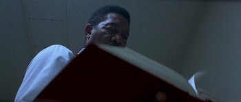 Movie still from “Kiss the Girls” (1997), directed by Gary Fleder – A person sitting at a table; Close Up shot, Low angle