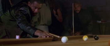 Movie still from “Kiss the Girls” (1997), directed by Gary Fleder – A man is playing pool while others watch; Medium shot, Over the shoulder angle