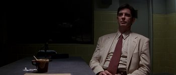 Movie still from “Kiss the Girls” (1997), directed by Gary Fleder – A man sitting at a table wearing a suit and tie; Medium shot, Low angle