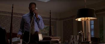 Movie still from “Kiss the Girls” (1997), directed by Gary Fleder – A man talking on a phone while standing in front of a desk; Medium shot, Low angle