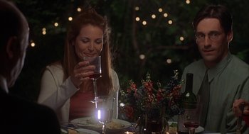 Movie still from “Kissing Jessica Stein” (2001), directed by Charles Herman-Wurmfeld – A woman holding a glass of wine at a dinner table; Medium shot, Over the shoulder angle