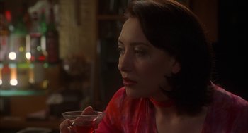 Movie still from “Kissing Jessica Stein” (2001), directed by Charles Herman-Wurmfeld – A woman sitting at a table holding a glass of wine; Close Up shot, Over the shoulder angle
