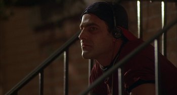 Movie still from “Kissing Jessica Stein” (2001), directed by Charles Herman-Wurmfeld – A man with headphones sitting on top of a railing; Close Up shot, Low angle
