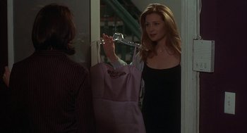 Movie still from “Kissing Jessica Stein” (2001), directed by Charles Herman-Wurmfeld – A woman holding onto a pink bag in front of a mirror; Medium shot, Over the shoulder angle