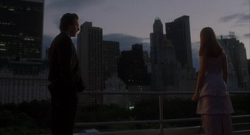 Movie still from “Kissing Jessica Stein” (2001), directed by Charles Herman-Wurmfeld – A man in a suit standing in front of a city skyline at night; Wide shot, Over the shoulder angle