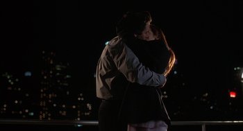 Movie still from “Kissing Jessica Stein” (2001), directed by Charles Herman-Wurmfeld – A man and a woman kissing in front of a city skyline at night; Medium shot, Low angle