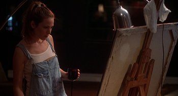 Movie still from “Kissing Jessica Stein” (2001), directed by Charles Herman-Wurmfeld – A woman standing in front of an easel holding a glass of wine; Medium shot, High angle