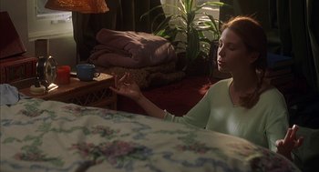 Movie still from “Kissing Jessica Stein” (2001), directed by Charles Herman-Wurmfeld – A woman sitting on a bed in a room with a plant; Medium shot, High angle
