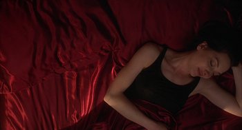 Movie still from “Kissing Jessica Stein” (2001), directed by Charles Herman-Wurmfeld – A woman laying on a bed with red sheets; Close Up shot, Overhead angle