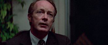 Movie still from “Klute” (1971), directed by Alan J. Pakula – A man in a suit and tie looking up; Close Up shot, Over the shoulder angle