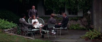 Movie still from “Klute” (1971), directed by Alan J. Pakula – A group of men and women sitting around a table; Wide shot, High angle