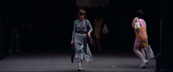 Movie still from “Klute” (1971), directed by Alan J. Pakula – A woman walking down a street holding a purse; Wide shot, Low angle