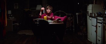 Movie still from “Klute” (1971), directed by Alan J. Pakula – A young girl sitting at a table holding a candle; Medium shot, High angle