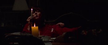 Movie still from “Klute” (1971), directed by Alan J. Pakula – A person sitting at a table with a candle and a glass of wine; Medium shot, Low angle