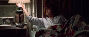 Movie still from “Klute” (1971), directed by Alan J. Pakula – A person sitting in a chair holding a remote control; Medium shot, Low angle