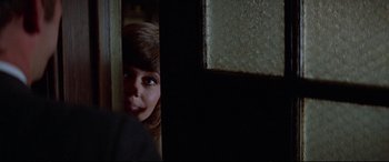 Movie still from “Klute” (1971), directed by Alan J. Pakula – A young woman peeking out from behind a wall; Close Up shot, Over the shoulder angle