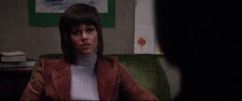 Movie still from “Klute” (1971), directed by Alan J. Pakula – A woman sitting on top of a green couch in a room; Close Up shot, Over the shoulder angle