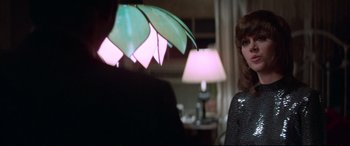 Movie still from “Klute” (1971), directed by Alan J. Pakula – A woman holding an umbrella in front of a man in a room; Close Up shot, Over the shoulder angle