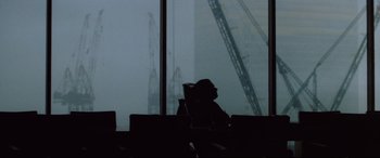 Movie still from “Klute” (1971), directed by Alan J. Pakula – A man sitting in a chair in front of a window; Extreme Wide shot, Low angle