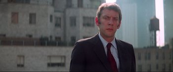 Movie still from “Klute” (1971), directed by Alan J. Pakula – A person wearing a suit and tie; Close Up shot, Low angle