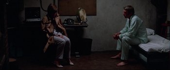 Movie still from “Klute” (1971), directed by Alan J. Pakula – Two people sitting on a bench in a room; Wide shot, High angle