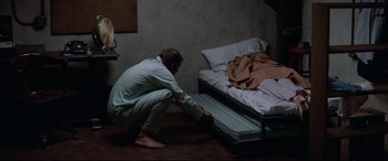 Movie still from “Klute” (1971), directed by Alan J. Pakula – A man kneeling down in front of a mattress; Wide shot, High angle