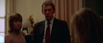 Movie still from “Klute” (1971), directed by Alan J. Pakula – A man wearing a suit and tie standing in a room; Close Up shot, Over the shoulder angle