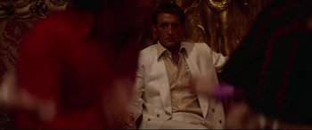 Movie still from “Klute” (1971), directed by Alan J. Pakula – A man in a white suit sitting in front of a gold wall; Medium shot, Low angle