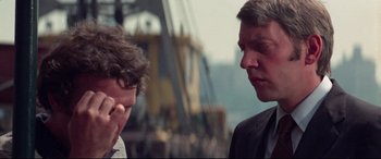 Movie still from “Klute” (1971), directed by Alan J. Pakula – Two men in business suits talking on a dock; Close Up shot, Over the shoulder angle