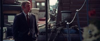 Movie still from “Klute” (1971), directed by Alan J. Pakula – A man standing next to ropes on a boat; Medium shot, Over the shoulder angle