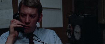Movie still from “Klute” (1971), directed by Alan J. Pakula – A man wearing a red tie sitting in front of a projector; Close Up shot, Low angle