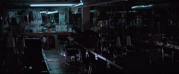 Movie still from “Klute” (1971), directed by Alan J. Pakula – A dark room filled with lots of tables and chairs; Wide shot, High angle