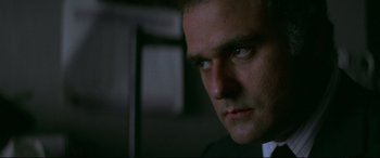 Movie still from “Klute” (1971), directed by Alan J. Pakula – A man in a suit looking at the camera; Close Up shot, Low angle