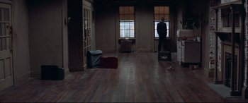 Movie still from “Klute” (1971), directed by Alan J. Pakula – A person standing in a room with luggage; Extreme Wide shot, High angle