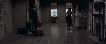 Movie still from “Klute” (1971), directed by Alan J. Pakula – A man and a woman standing in an empty room with suitcases; Wide shot, High angle