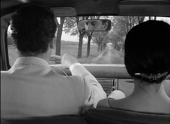 Movie still from “Knife in the Water” (1962), directed by Roman Polanski – A man and a woman driving a car down a dirt road; Close Up shot, Over the shoulder angle