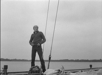 Movie still from “Knife in the Water” (1962), directed by Roman Polanski – A black and white photo of a man standing on a boat; Medium shot, Low angle