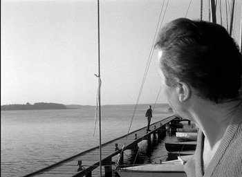 Movie still from “Knife in the Water” (1962), directed by Roman Polanski – A man looking out over a body of water; Medium shot, Over the shoulder angle