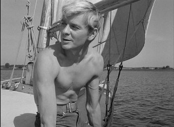 Movie still from “Knife in the Water” (1962), directed by Roman Polanski – A shirtless man standing on a boat in the water; Medium shot, Low angle